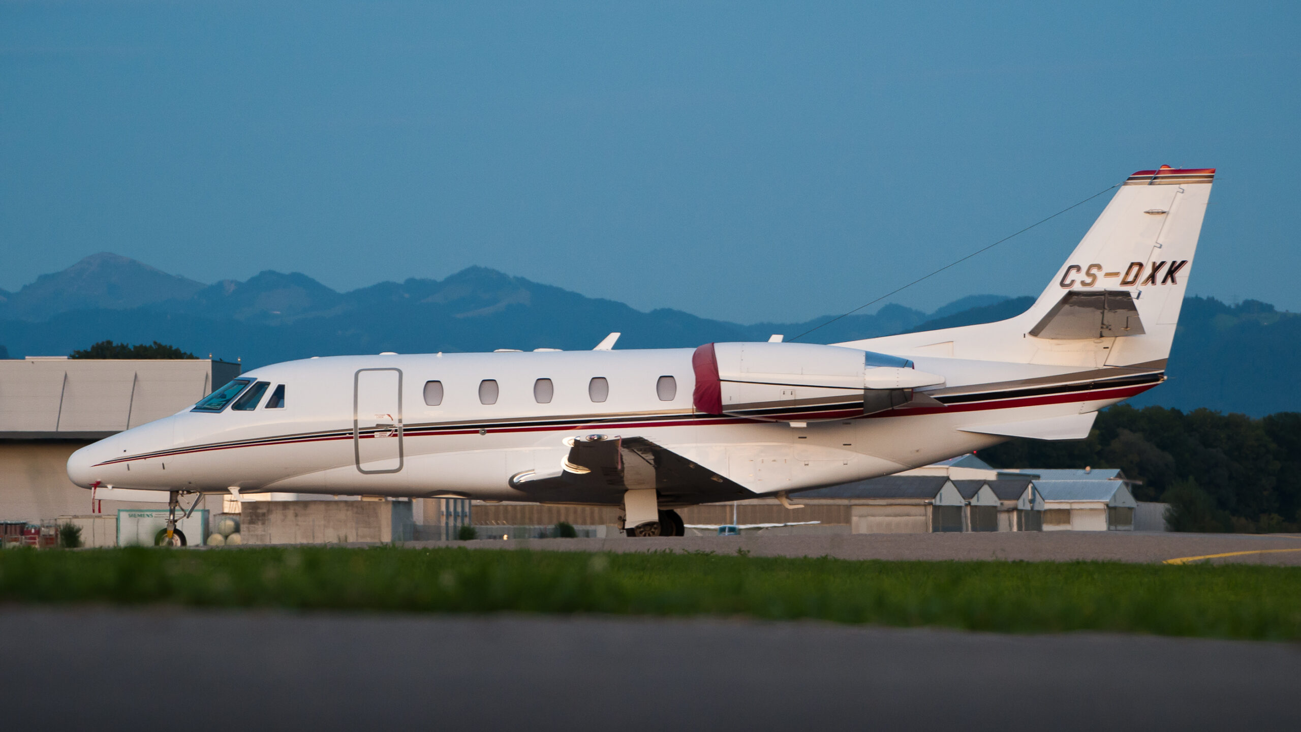 A business jet parked on the ramp with a mountain ridge behind it