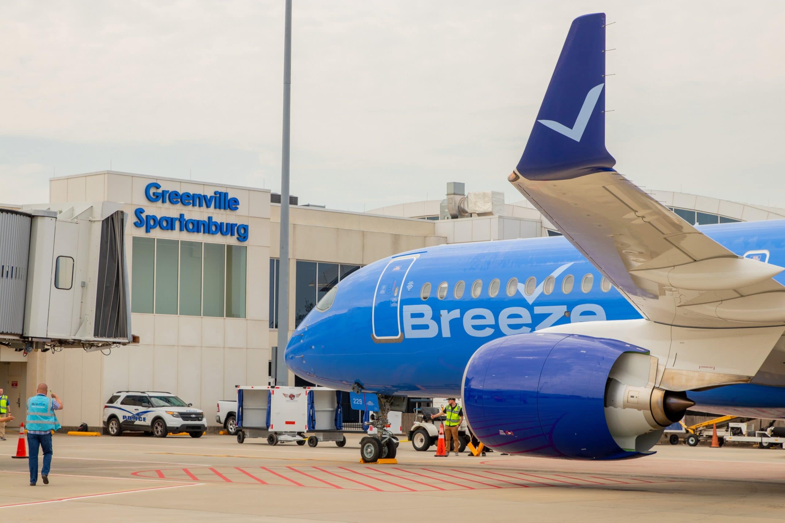 A Breeze Airways aircraft parked at a jet bridge gate at GSP.